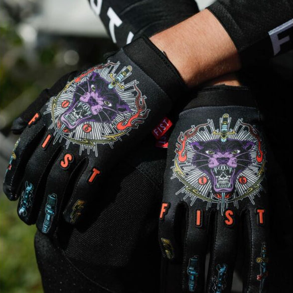 Black gloves with colorful designs and 'Fist' branding worn by a person.