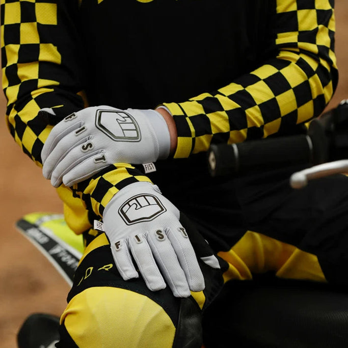 Person wearing a black and yellow checkered jacket with 'FORTH' branding, sitting on a dirt bike.