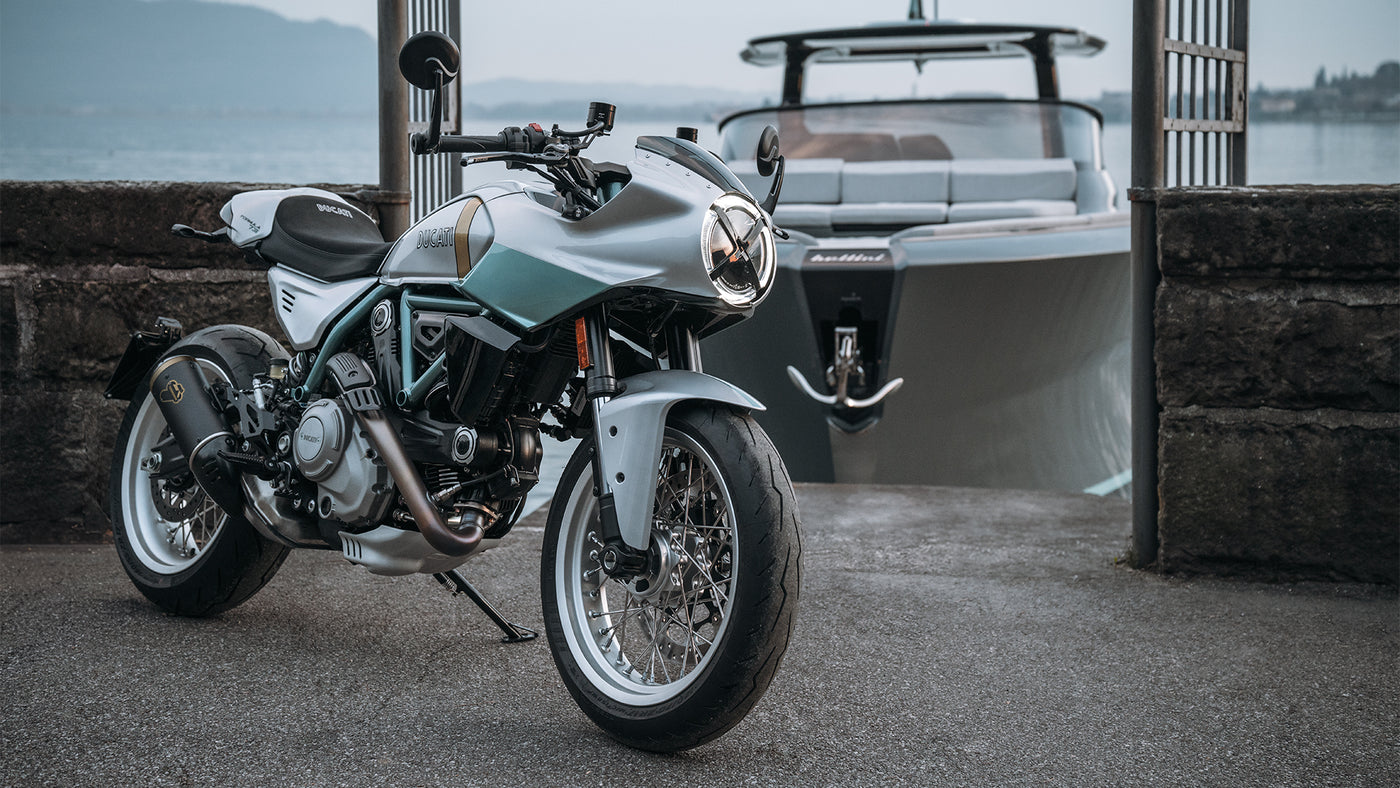 Motorcycle parked on a dock with a boat in the background
